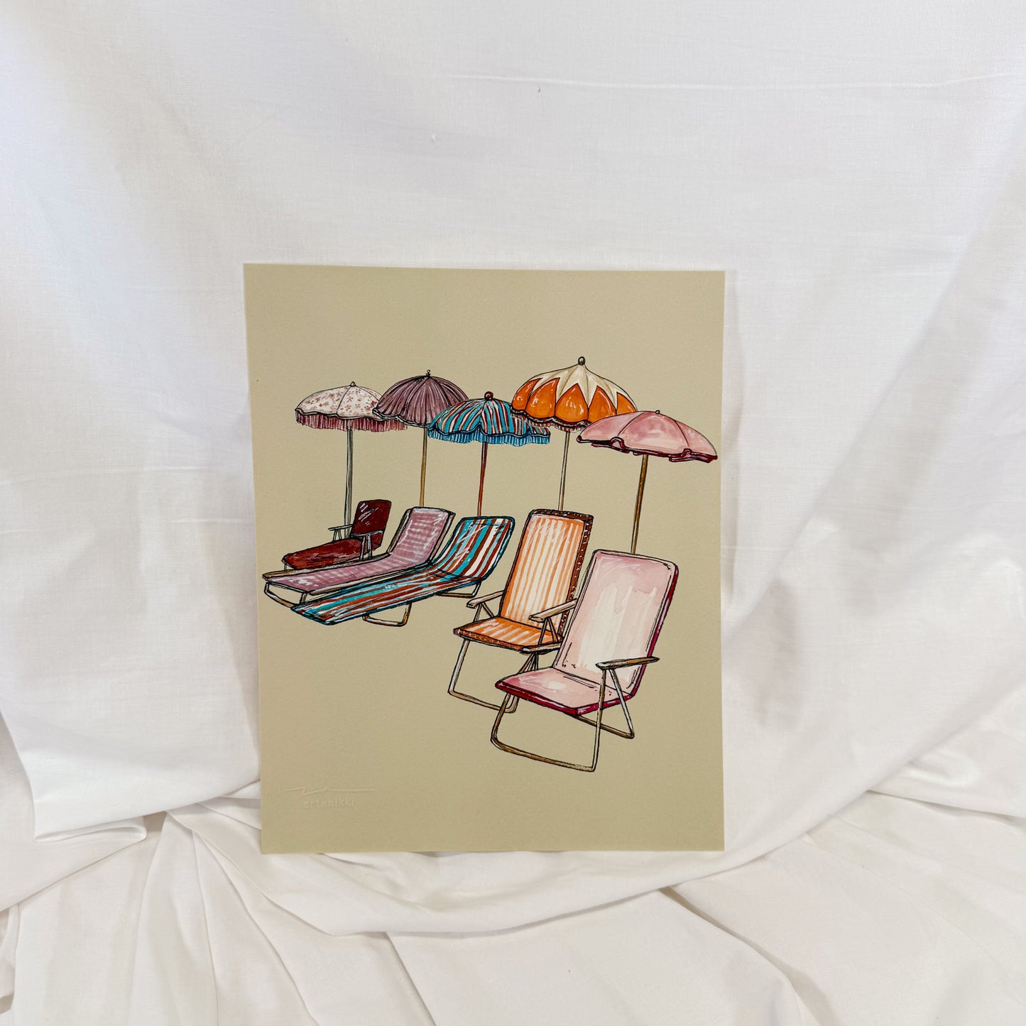Wall art print of colorful beach chairs on a sandy colored backgorund.