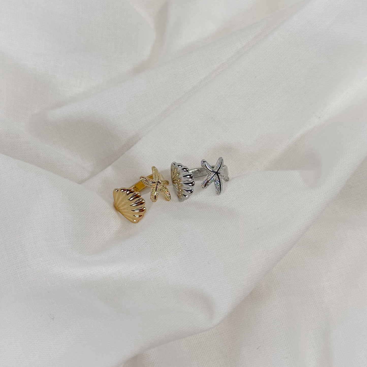 Jewelry set with a starfish and shell charm on a white fabric background
