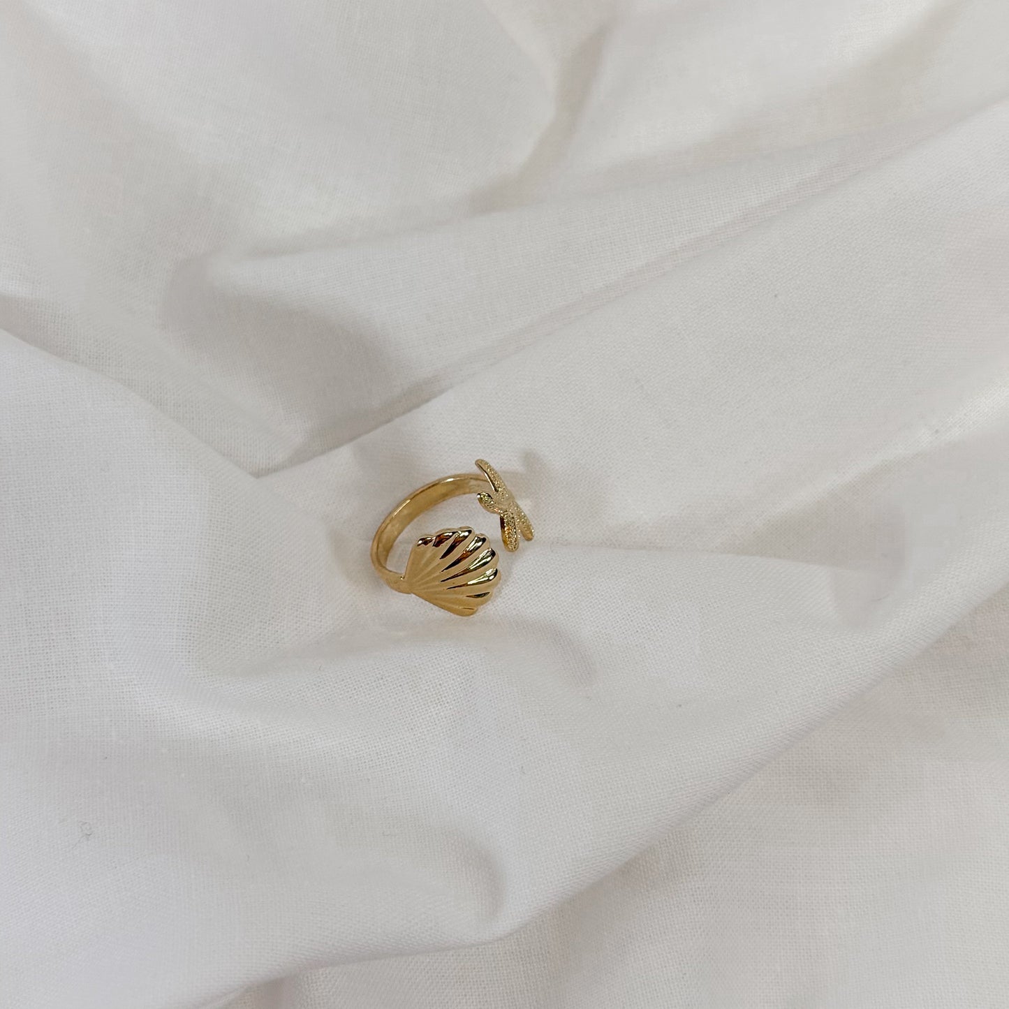 Gold ring with shell design on a white fabric background