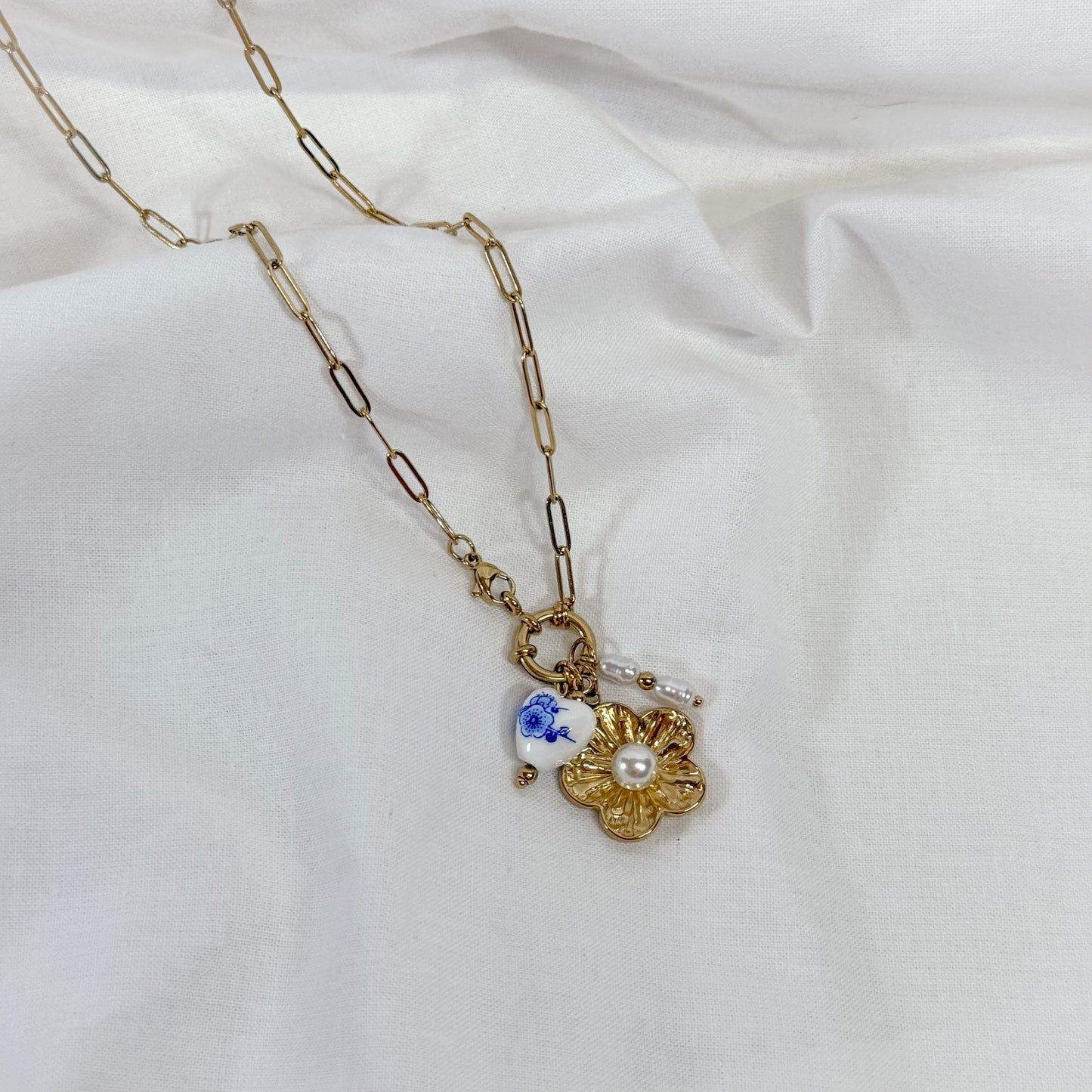 Gold chain necklace with a floral pendant on a white background