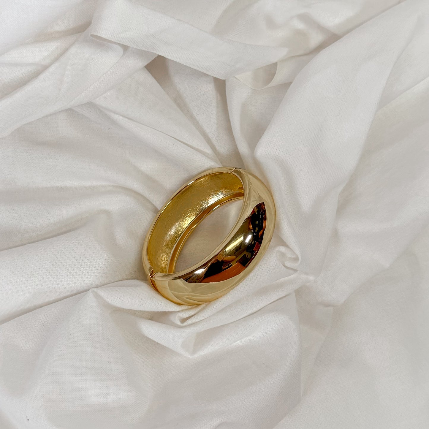Gold bracelet on a white fabric background