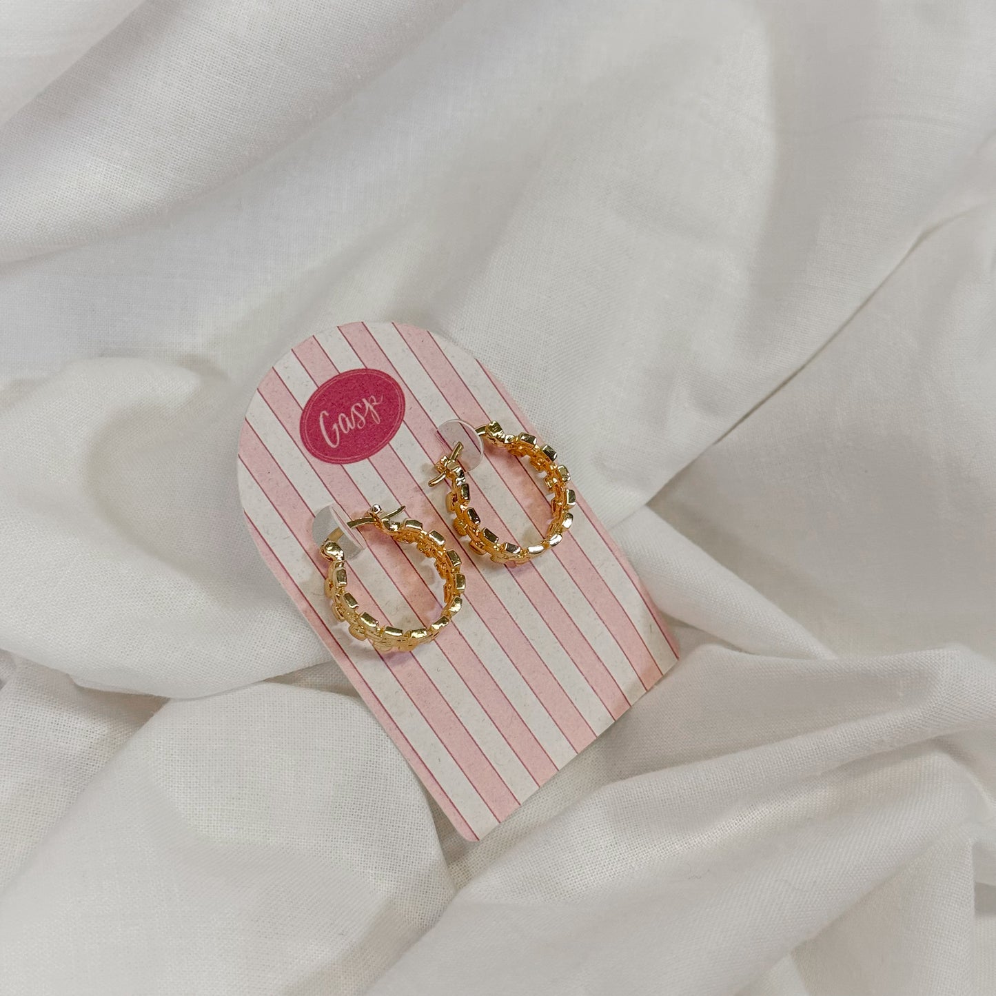 Gold chain hoop earrings on a pink and white striped card with 'Gasp' branding, against a white fabric background.
