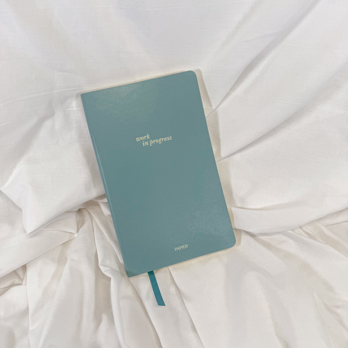 Stylish vegan leather lined notebook in light blue with inspirational quote on the cover