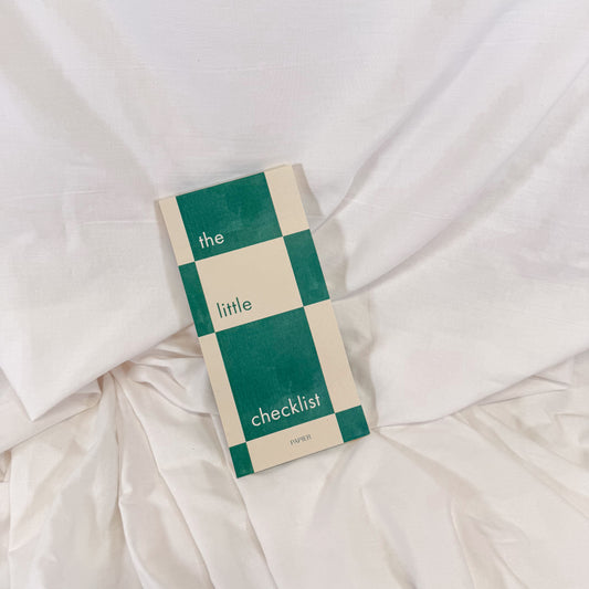 Checklist to do list notepad with green and beige checkered design on a white fabric background