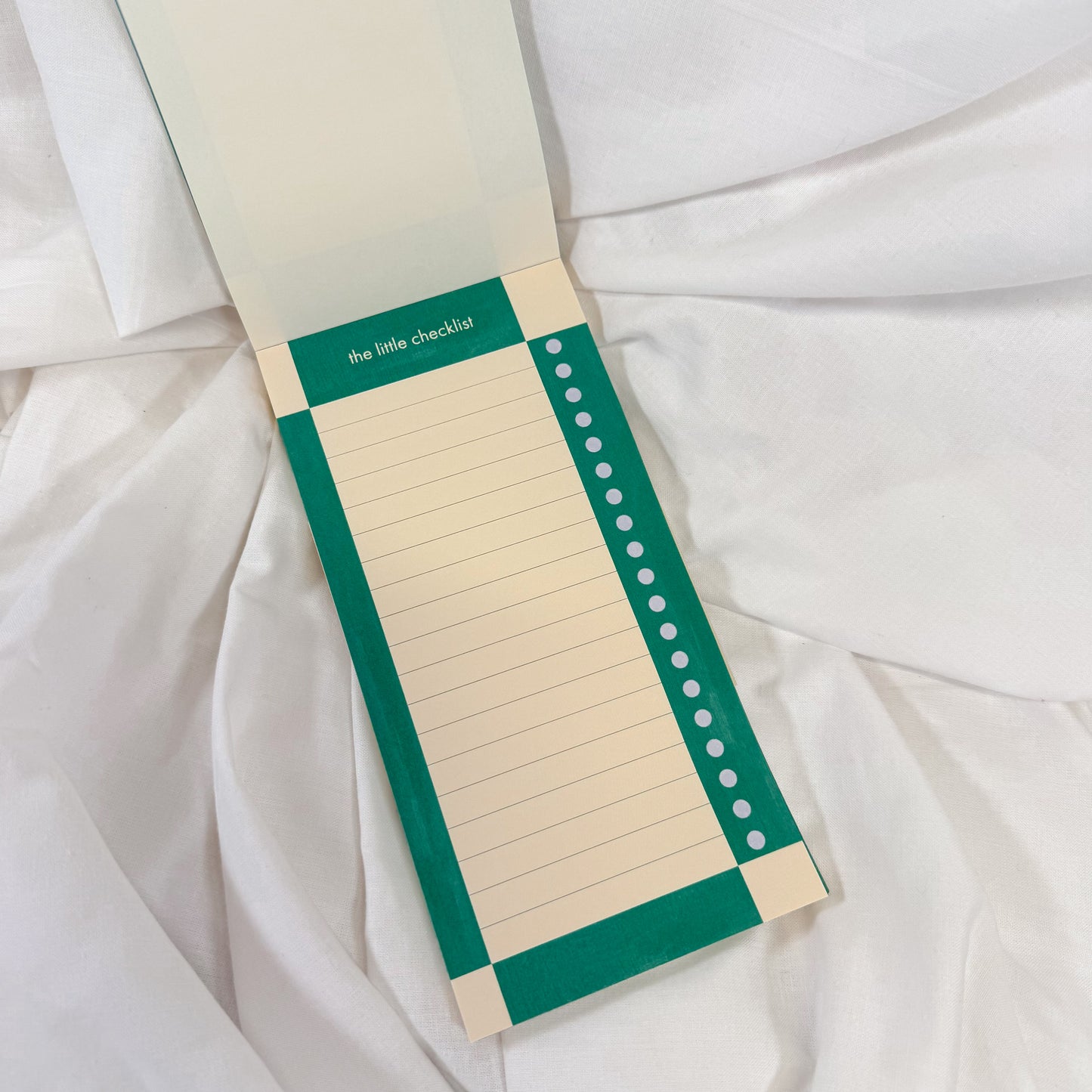 To Do List Notepad with green border and white pages on a white fabric background