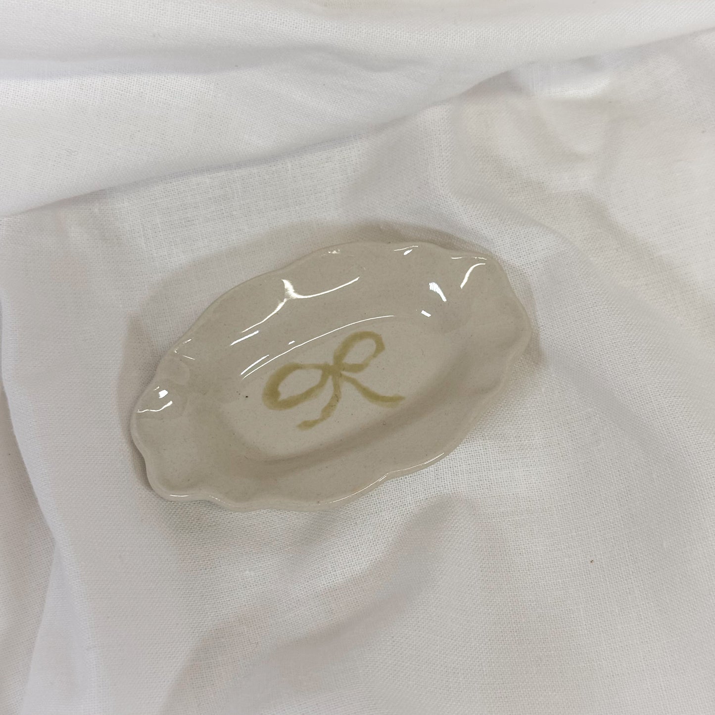Small white dish with a yellow dainty bow on a white fabric background