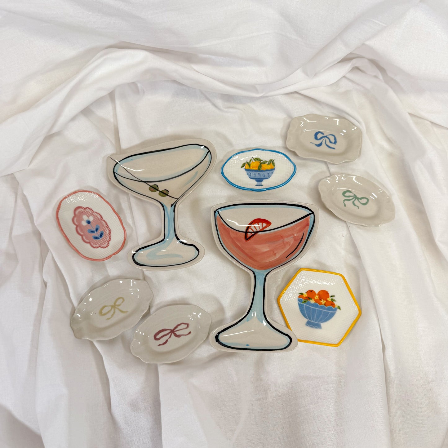 Set of decorative ceramic trinket dishes with various colorful designs on a white fabric background