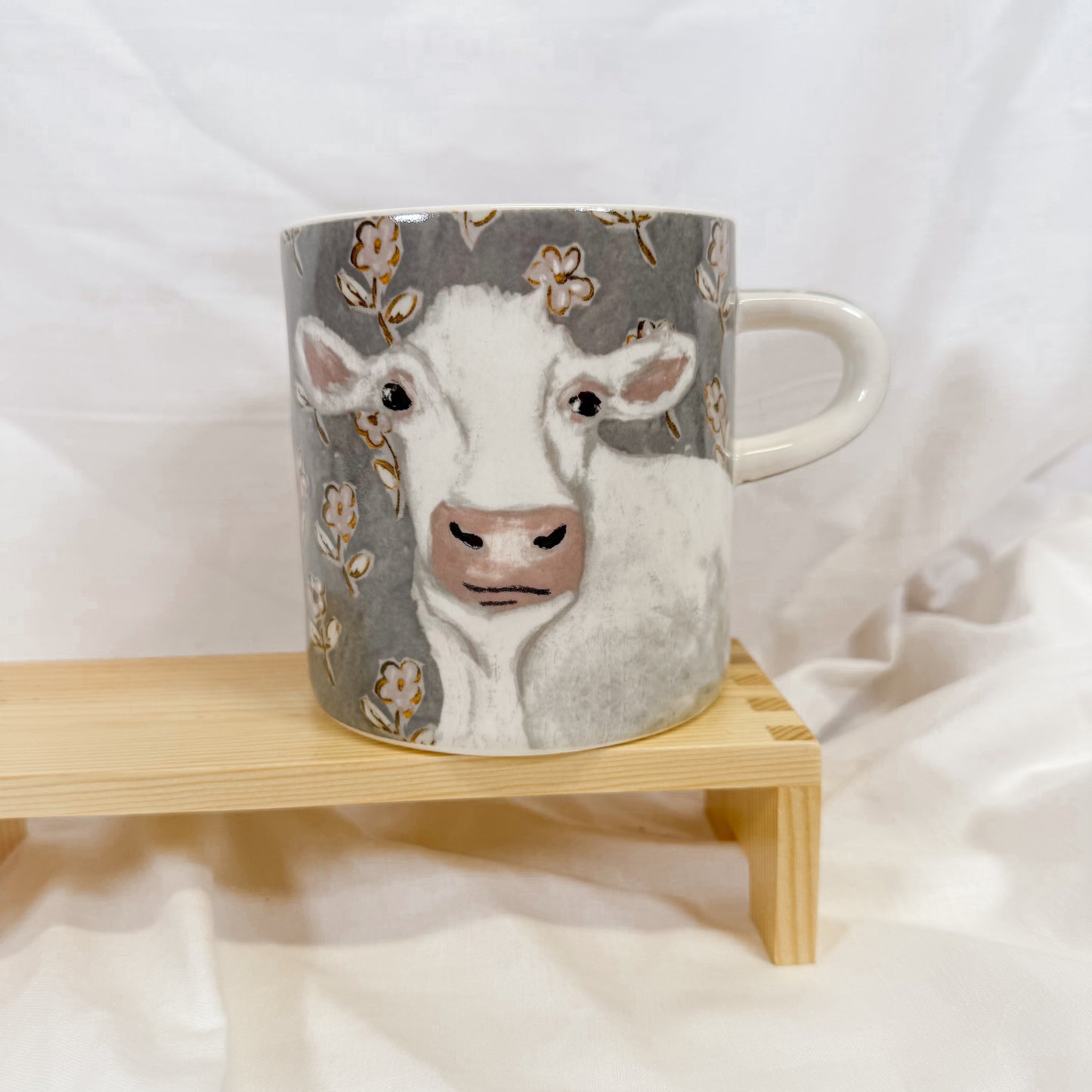 Mug with a cow design on a wooden stand against a white background