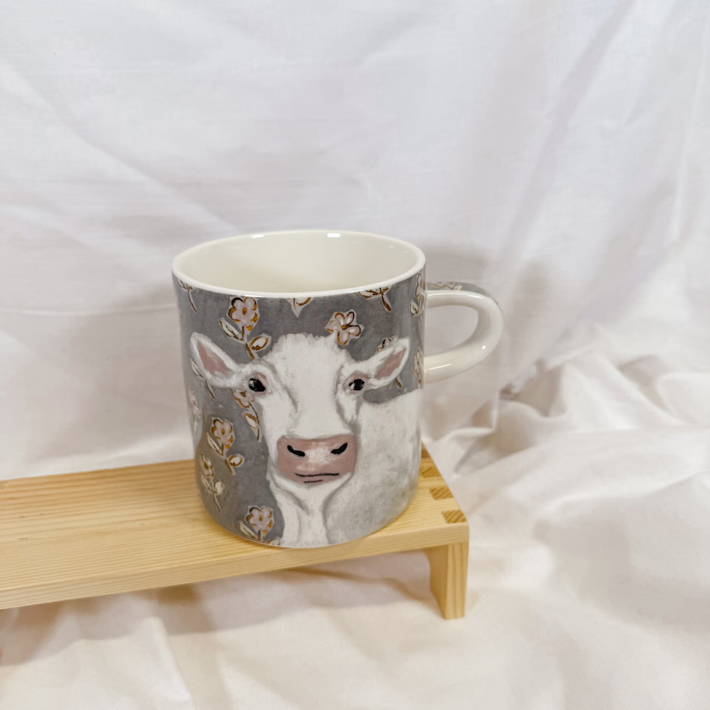 Mug with cow design on a wooden stand against a white background