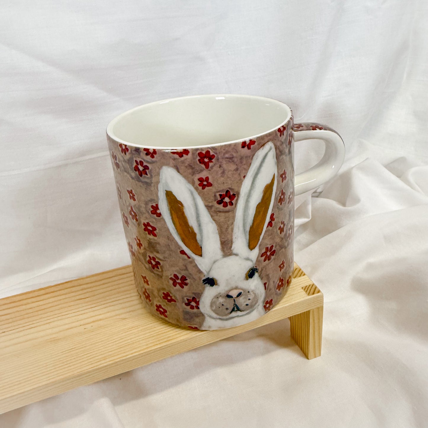 Mug with rabbit design on a wooden stand against a white background
