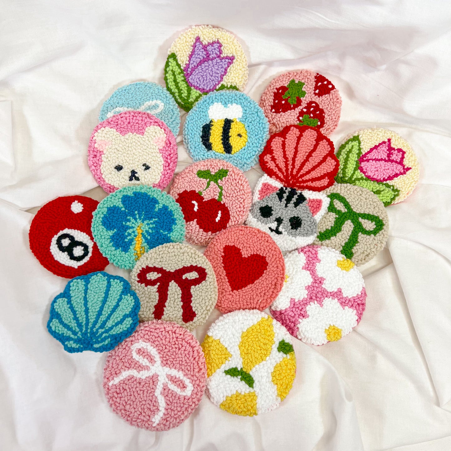 Assorted handmade punch needle car coasters with colorful and trendy designs including flowers, animals, fruit, hearts, and bows – aesthetic knit cup holder inserts for car interior decor