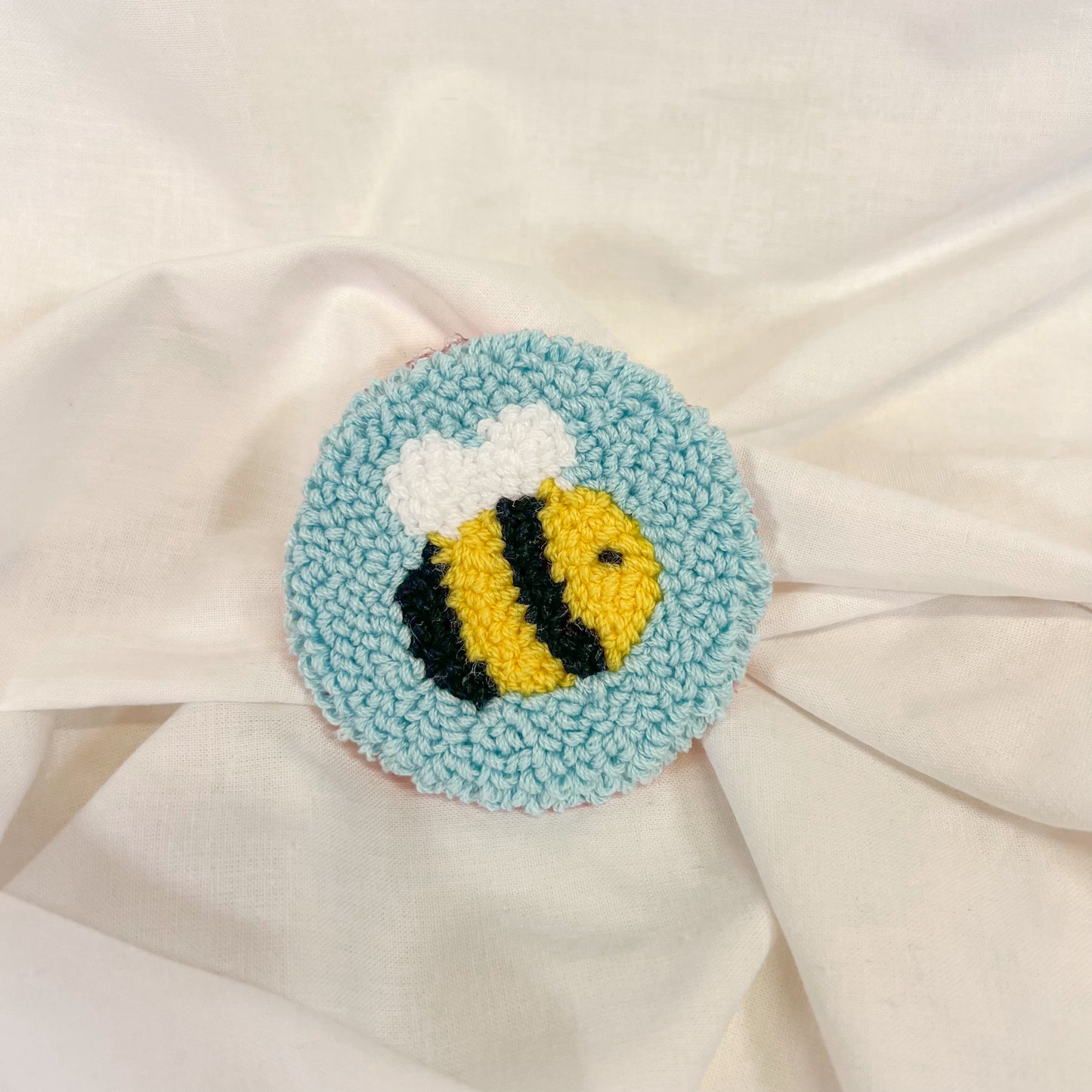Round car cup holder insert a bee design on a white fabric background