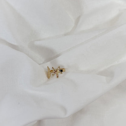 Gold starfish-shaped ring on a white fabric background