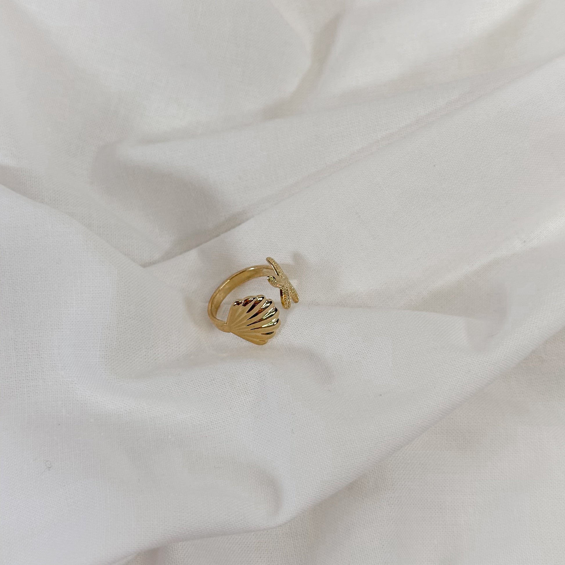 Gold ring with shell design on a white fabric background