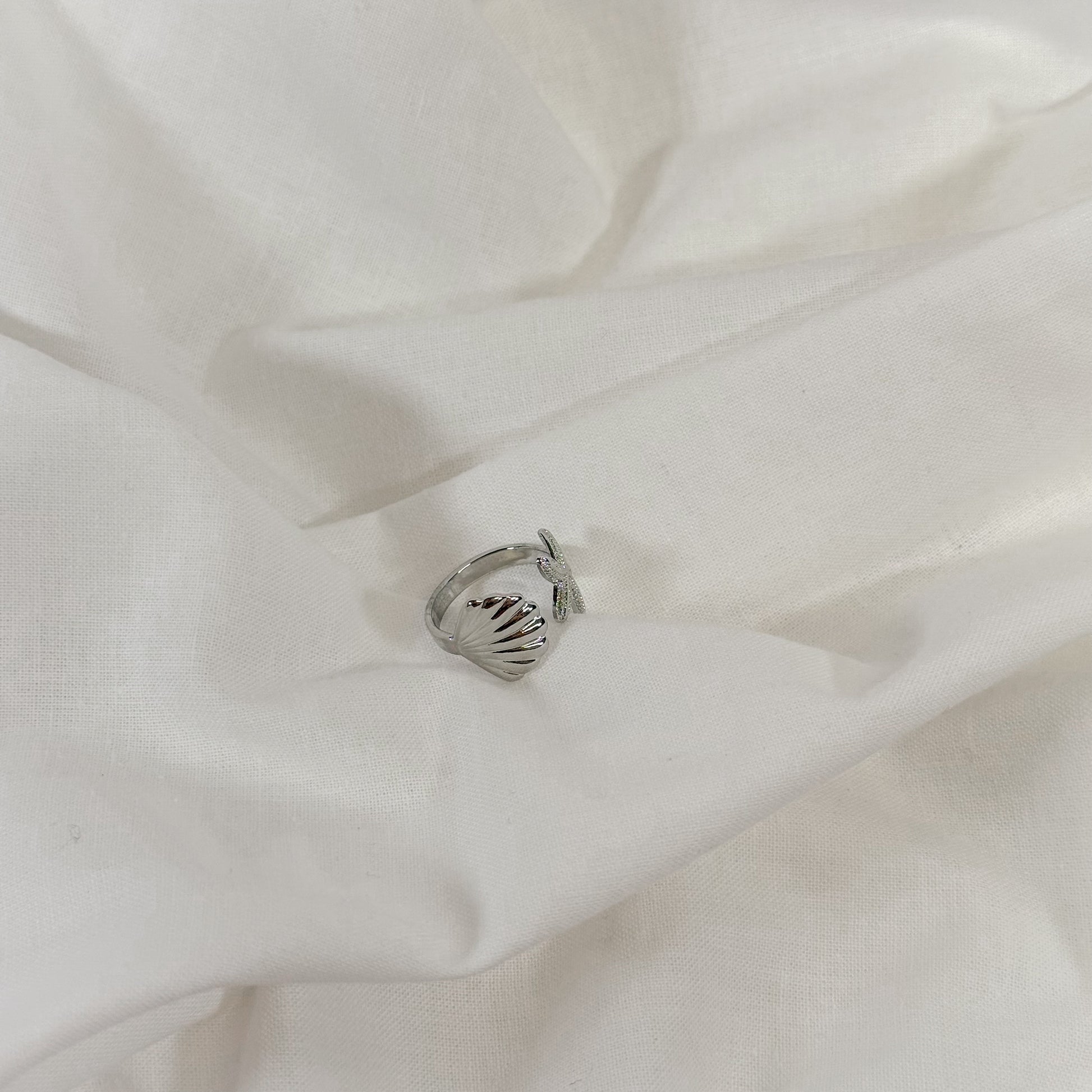 Silver ocean themed ring on a white fabric background