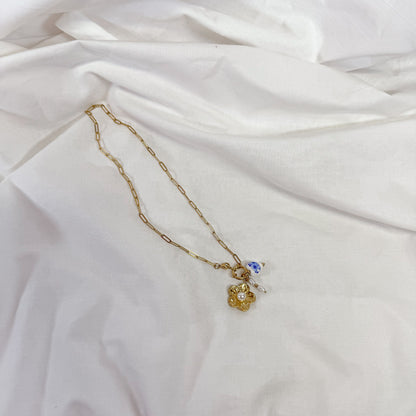 Gold necklace with a porcelain flower pendant on a white fabric background