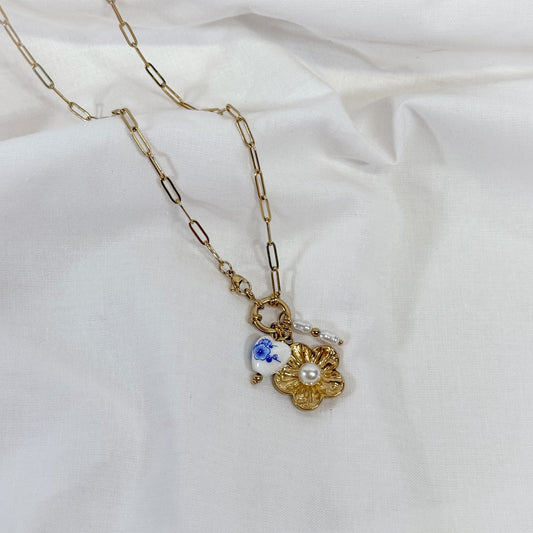 Gold chain necklace with a floral pendant on a white background