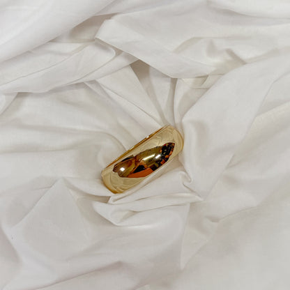 Chunky gold bracelet on a white fabric background