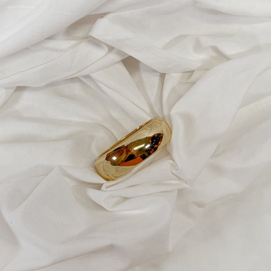 Chunky gold bracelet on a white fabric background