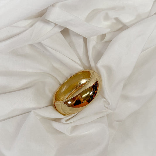 Gold bangle bracelet on a white fabric background