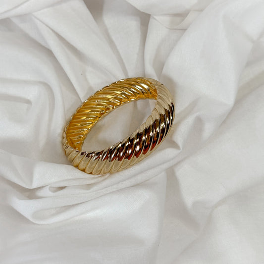 Twisted gold bangle bracelet on a white background