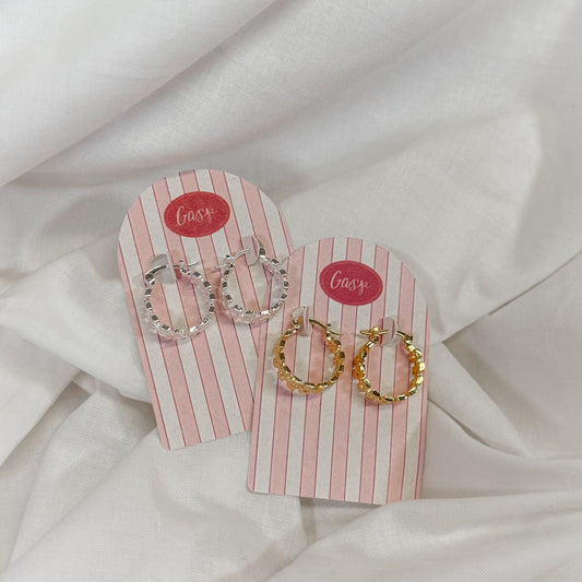 Pair of hoop earrings on a pink striped card with 'Gasp' branding, set against a white fabric background.