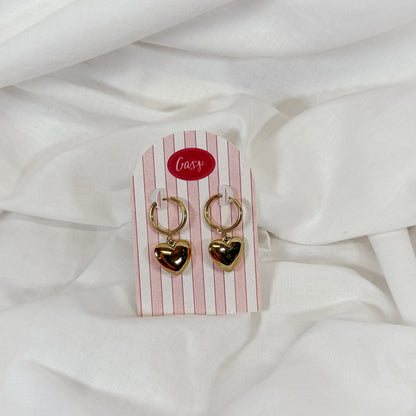 Gold chunky heart-shaped hoop earrings on a striped card with 'Gasp' logo against a white fabric background