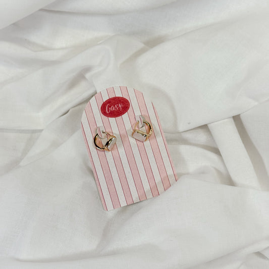 Pair of gold and pearl hoop earrings on a pink and white striped card with 'Gasp' branding, placed on a white fabric background.