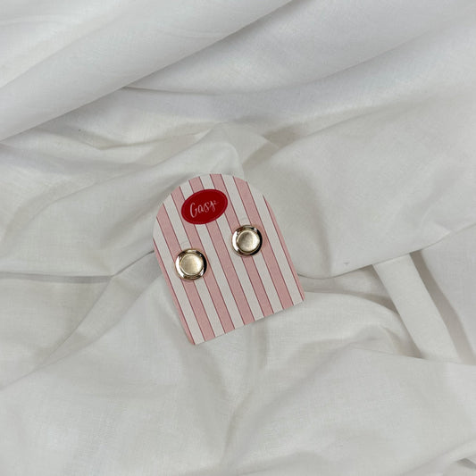 Flat gold earrings on a white fabric background