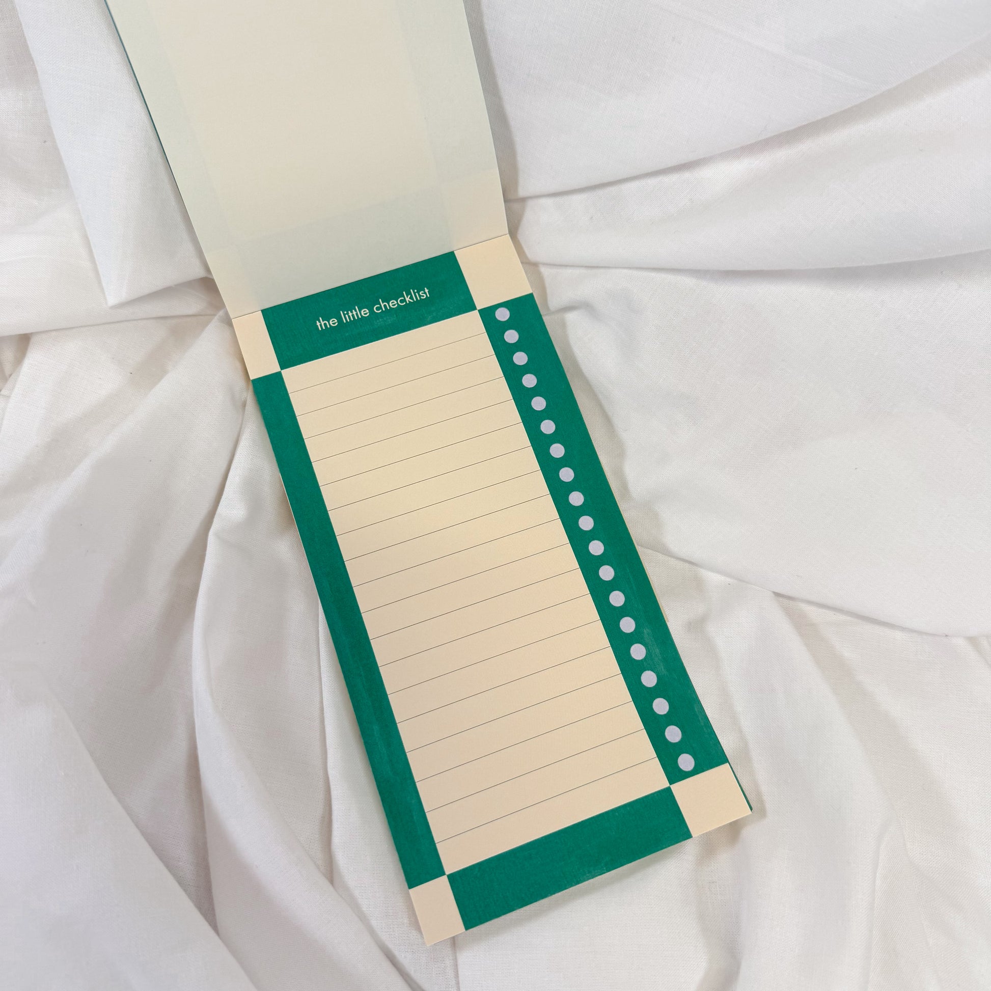 To Do List Notepad with green border and white pages on a white fabric background