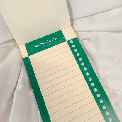Aesthetic green checkered notepad for daily tasks, open on a white fabric background