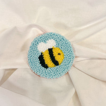 Round car cup holder insert a bee design on a white fabric background